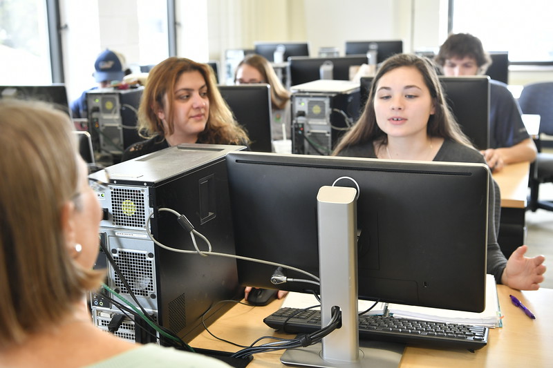 two students and a librarian working on a computer