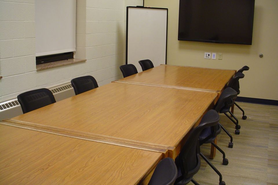 room with tables, chairs, white board, screen, and computer.